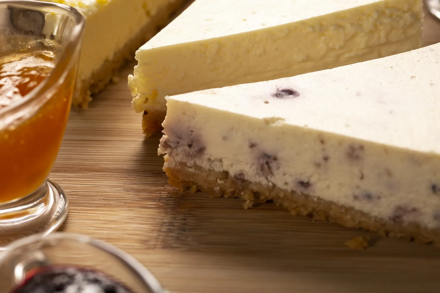 Fatias de cheesecake estilo americano sobre a tábua, com potes de calda